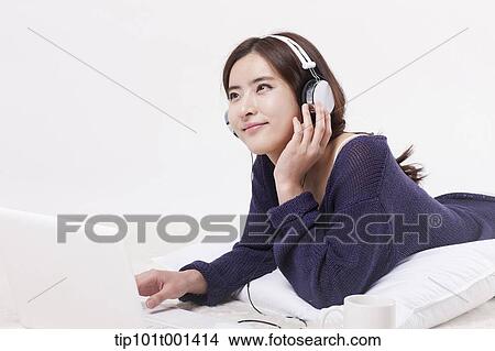 a woman lying on a carpet listening to music View Large Photo Image Picture - a woman lying on a carpet listening to music. Fotosearch