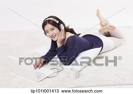 a woman lying on a carpet listening to music View Large Photo Image Stock Image - a woman lying on a carpet listening to music. Fotosearch