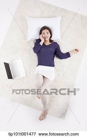 Stock Photo - a woman lying on a pillow talking on a mobile phone. Fotosearch
