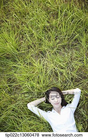 Stock Photo - a woman lying on the grass. Fotosearch