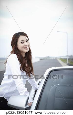 Stock Photo - a woman next to a convertible car. Fotosearch