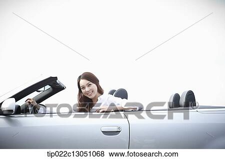 Stock Photo - a woman next to a convertible car. Fotosearch