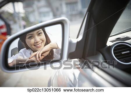 Stock Photograph - a woman next to a convertible car. Fotosearch