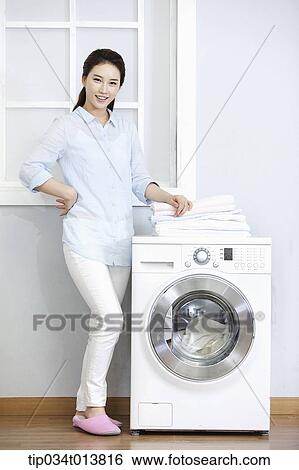 Stock Photograph - a woman next to washing machine. Fotosearch