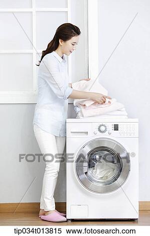 Stock Photography - a woman next to washing machine. Fotosearch