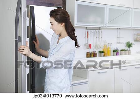 a woman opening the refrigerator in the kitchen View Large Photo Image Stock Photo - a woman opening the refrigerator in the kitchen. Fotosearch