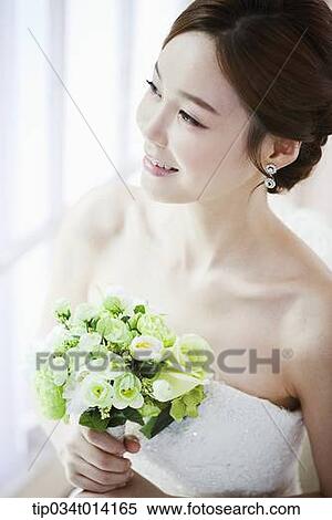 Stock Photography - a woman posing with wedding dress and flower bouquet. Fotosearch