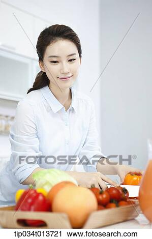 Stock Image - a woman putting vegetables and fruits on a tray. Fotosearch
