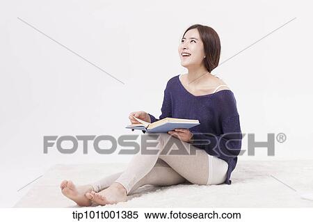 Stock Photography - a woman sitting on a carpet reading a book. Fotosearch