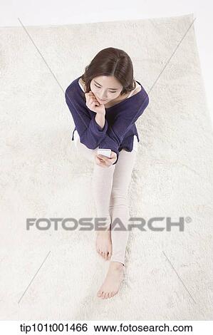 a woman sitting on a carpet using a mobile phone View Large Photo Image Stock Photograph - a woman sitting on a carpet using a mobile phone. Fotosearch