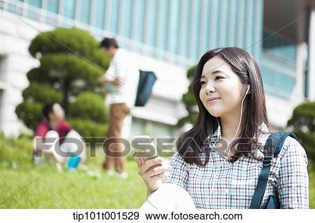 a woman sitting on a grass listening to music View Large Photo Image Stock Photo - a woman sitting on a grass listening to music. Fotosearch