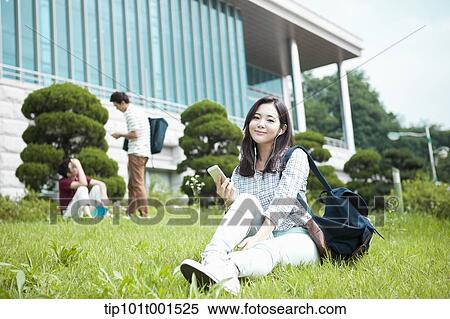 a woman sitting on a grass listening to music View Large Photo Image Stock Photography - a woman sitting on a grass listening to music. Fotosearch