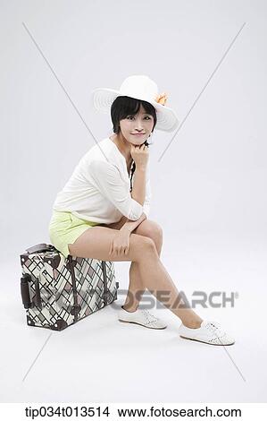 a woman sitting on a suitcase posing View Large Photo Image Picture - a woman sitting on a suitcase posing. Fotosearch