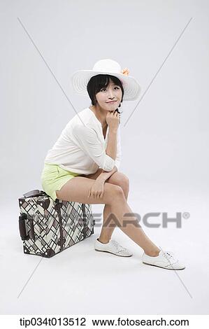 a woman sitting on a suitcase posing View Large Photo Image Stock Image - a woman sitting on a suitcase posing. Fotosearch