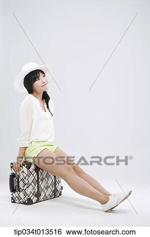 a woman sitting on a suitcase posing View Large Photo Image Stock Photograph - a woman sitting on a suitcase posing. Fotosearch