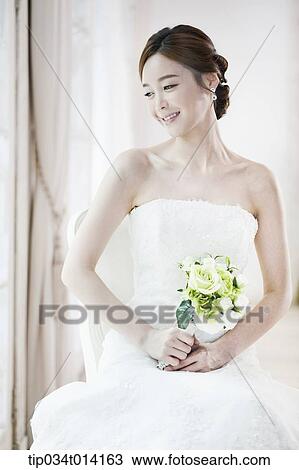 Stock Image - a woman sitting on the floor with wedding dress on. Fotosearch