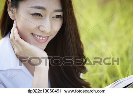 a woman sitting on the grass reading a book View Large Photo Image Stock Image - a woman sitting on the grass reading a book. Fotosearch