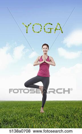 Stock Photo - a woman standing with one leg next to word yoga. Fotosearch