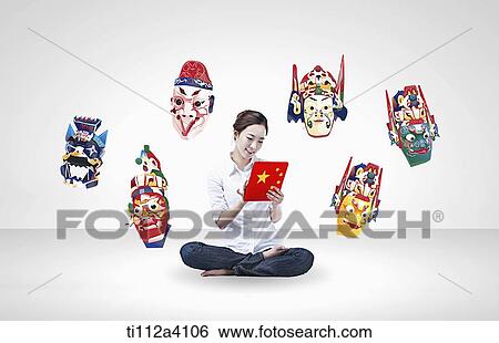 Stock Photograph - a woman surrounded by Chinese masks. Fotosearch