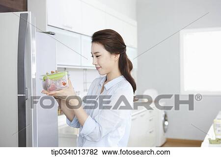 a woman taking out food from refrigerator in the kitchen View Large Photo Image Stock Image - a woman taking out food from refrigerator in the kitchen. Fotosearch