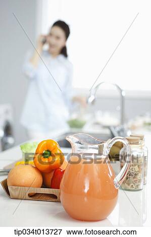 Stock Photo - a woman talking on the phone while cooking. Fotosearch