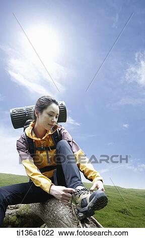 Stock Image - a woman tying her shoes while hiking. Fotosearch
