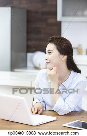 a woman using laptop in the kitchen View Large Photo Image Stock Photo - a woman using laptop in the kitchen. Fotosearch