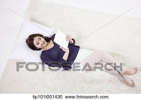a woman using tablet PC while lying on a pillow View Large Photo Image Stock Image - a woman using tablet PC while lying on a pillow. Fotosearch