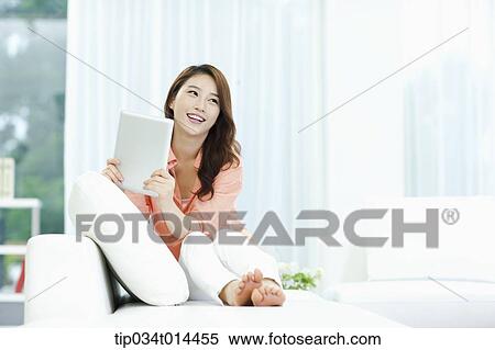 a woman using tablet PC white sitting on a couch View Large Photo Image Stock Photography - a woman using tablet PC white sitting on a couch . Fotosearch