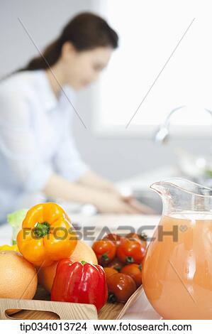 a woman washing in the sink behind tray of vegetables and fruits View Large Photo Image Picture - a woman washing in the sink behind tray of vegetables and fruits. Fotosearch