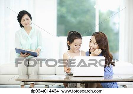 Picture - a woman watching daughter and grand daughter using laptop. Fotosearch