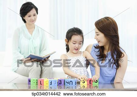 Stock Image - a woman watching daughter and grand daughter playing together. Fotosearch