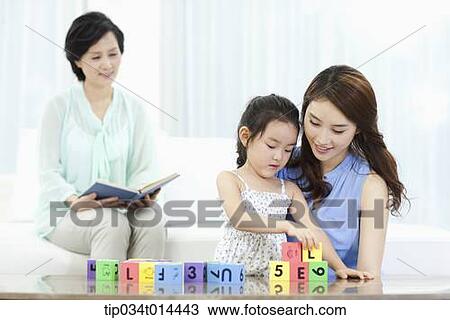 Stock Image - a woman watching daughter and grand daughter playing together. Fotosearch