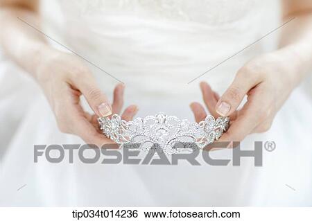 Stock Photograph - a woman wearing a wedding dress holding wedding crown. Fotosearch