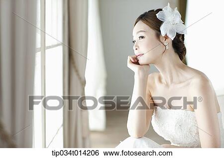 Stock Photograph - a woman wearing wedding dress looking out the window. Fotosearch