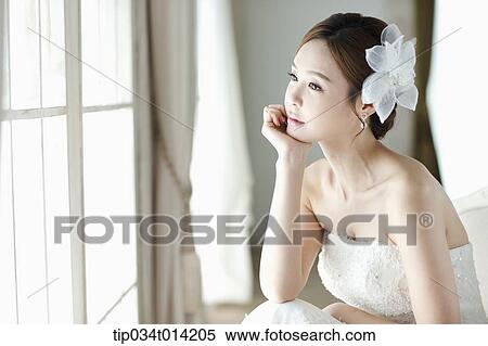 Stock Photography - a woman wearing wedding dress looking out the window. Fotosearch