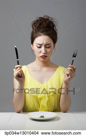 Picture - a woman with a plate with a small amount of food. Fotosearch