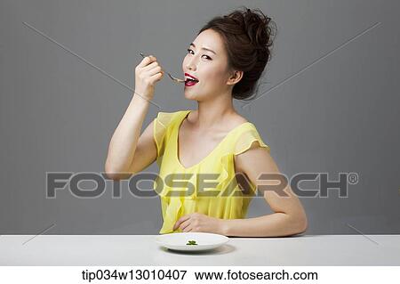 Stock Photo - a woman with a plate with a small amount of food. Fotosearch