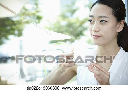 a woman with a white shirt drinking coffee View Large Photo Image Stock Photograph - a woman with a white shirt drinking coffee. Fotosearch
