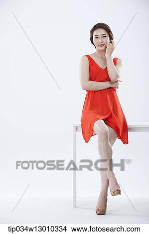 a woman with an orange dress leaning on a table View Large Photo Image Picture - a woman with an orange dress leaning on a table. Fotosearch