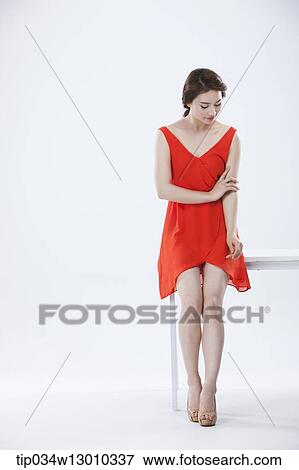 a woman with an orange dress leaning on a table View Large Photo Image Stock Photo - a woman with an orange dress leaning on a table. Fotosearch