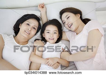 Stock Photo - a woman with daughter and grand daughter on a bed. Fotosearch