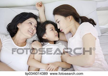 Stock Photo - a woman with daughter and grand daughter on a bed. Fotosearch