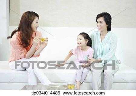 Stock Photograph - a woman with daughter and grand daughter in the living room . Fotosearch