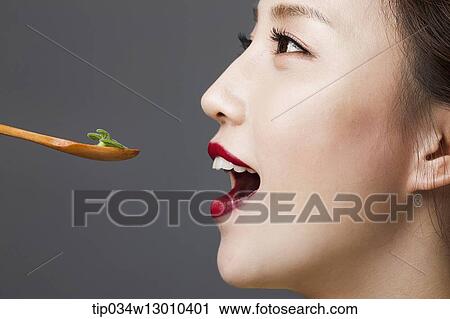 Stock Image - a woman with her mouth open next to a spoon. Fotosearch