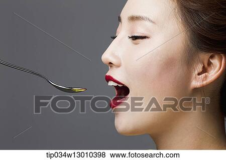 Stock Photo - a woman with her mouth open next to a spoon. Fotosearch