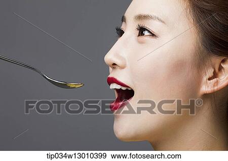 Stock Photo - a woman with her mouth open next to a spoon. Fotosearch