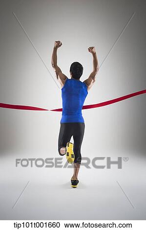 Stock Image - back shot of a fit man in blue shirt running to a finishing line. Fotosearch