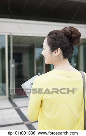 back shot of a woman going into a building holding books View Large Photo Image Stock Photo - back shot of a woman going into a building holding books . Fotosearch