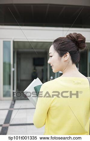 back shot of a woman going into a building holding books View Large Photo Image Stock Photography - back shot of a woman going into a building holding books . Fotosearch